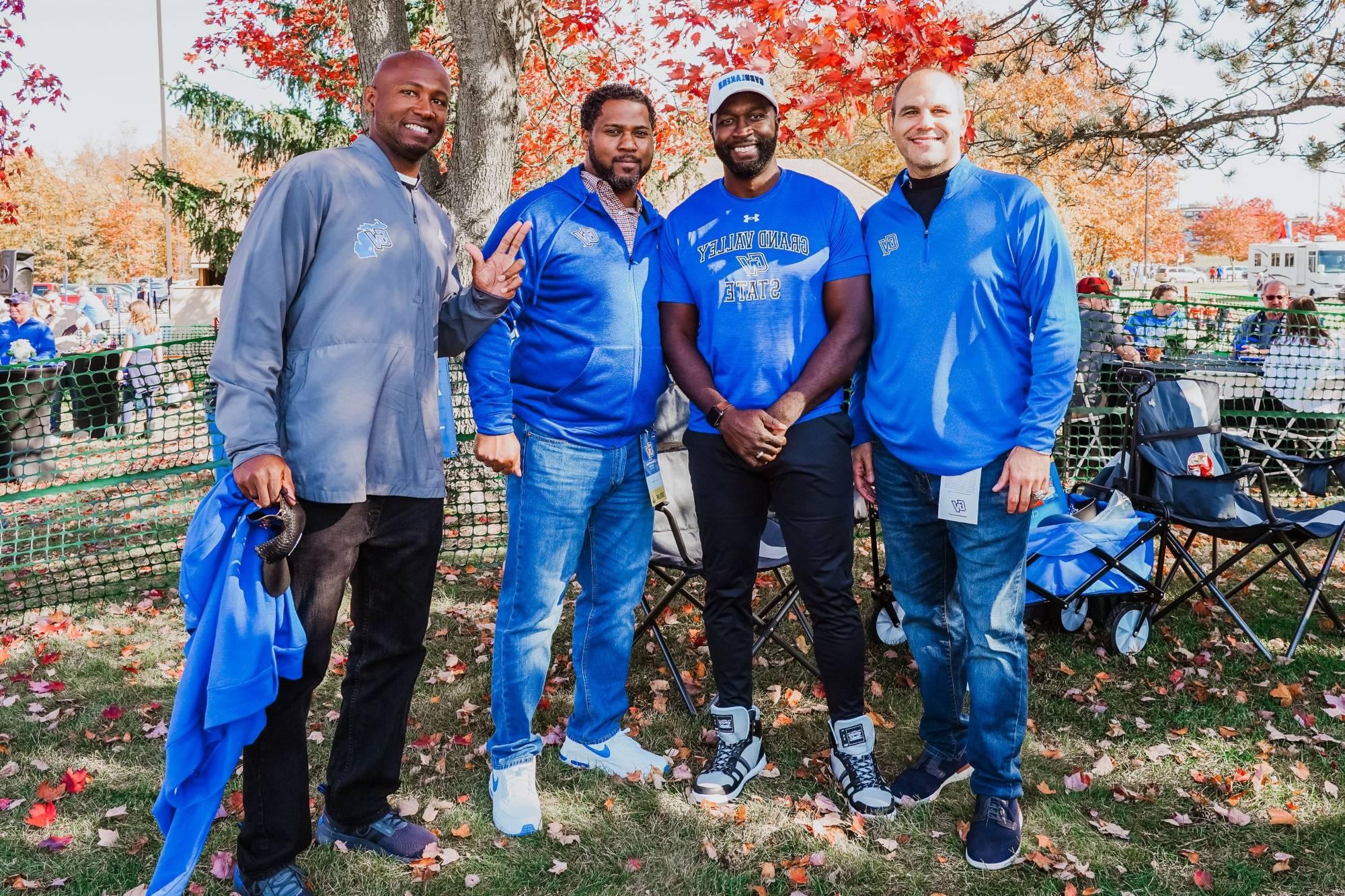 A group of alumni smile and anchor up during the Homecoming tailgate